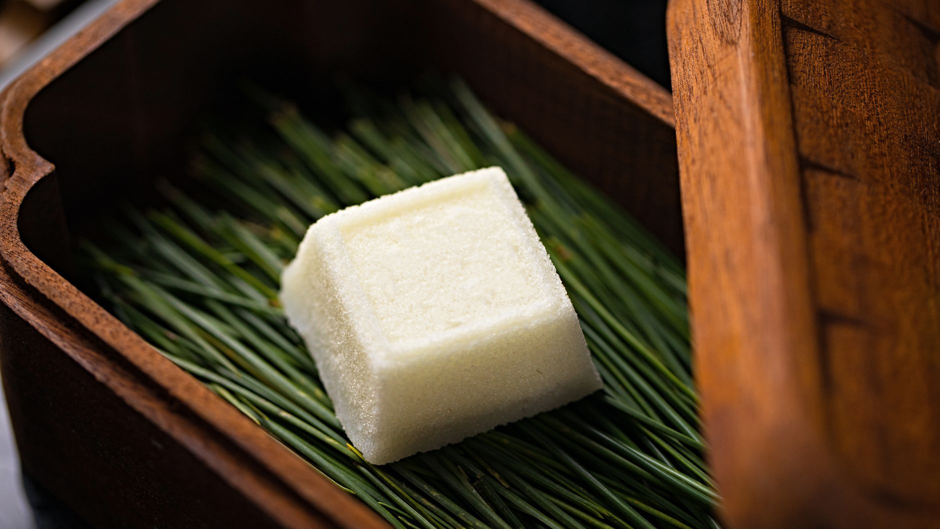 A white Japanese sweet on pine needles in a wooden box