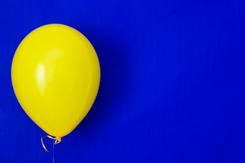 Free A vibrant yellow balloon on a striking blue background, perfect for various celebratory themes. Stock Photo