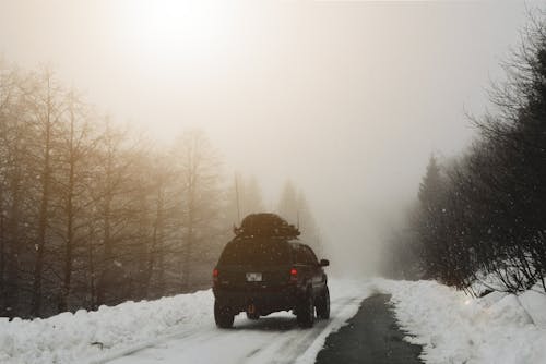 Черный автомобиль, едущий по заснеженной дороге