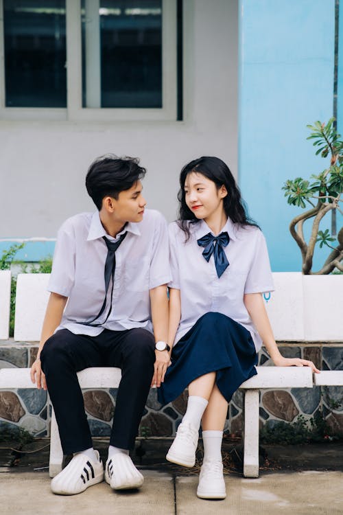A couple sitting on a bench in front of a school