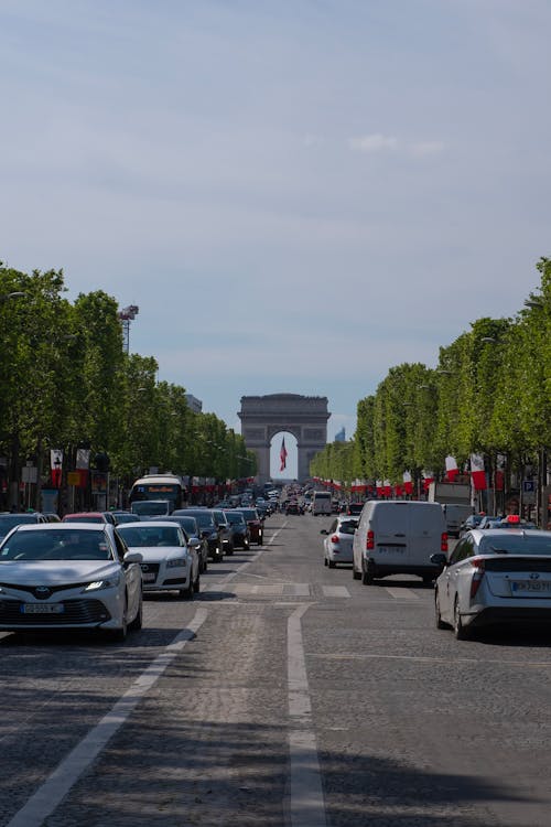 Cars are driving down a street in front of the arc de trios