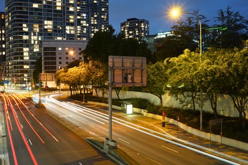 Free A dynamic cityscape of Sydney at night showcasing vibrant light trails on the highway with skyscrapers in the background. Stock Photo