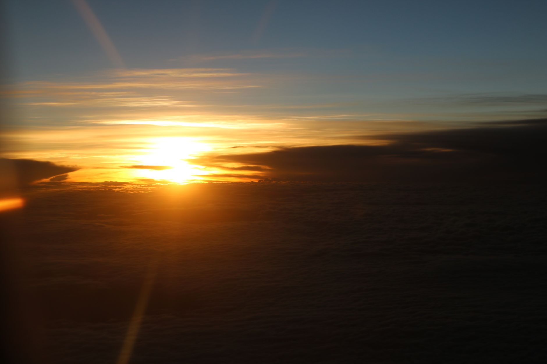 A breathtaking aerial view of the sun setting over a vast cloudscape, casting a warm glow across the sky.