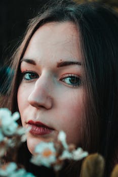 自然光下拍摄的花朵中，年轻女子的亲密特写