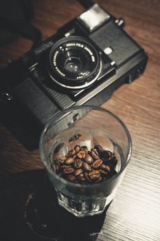 Close-up of a vintage camera with a glass of coffee beans on a wooden table