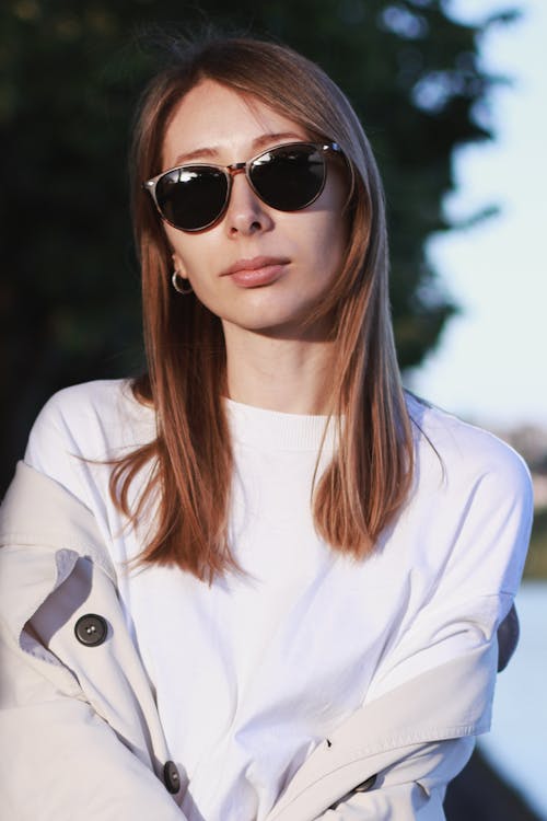 A woman wearing sunglasses and a white shirt