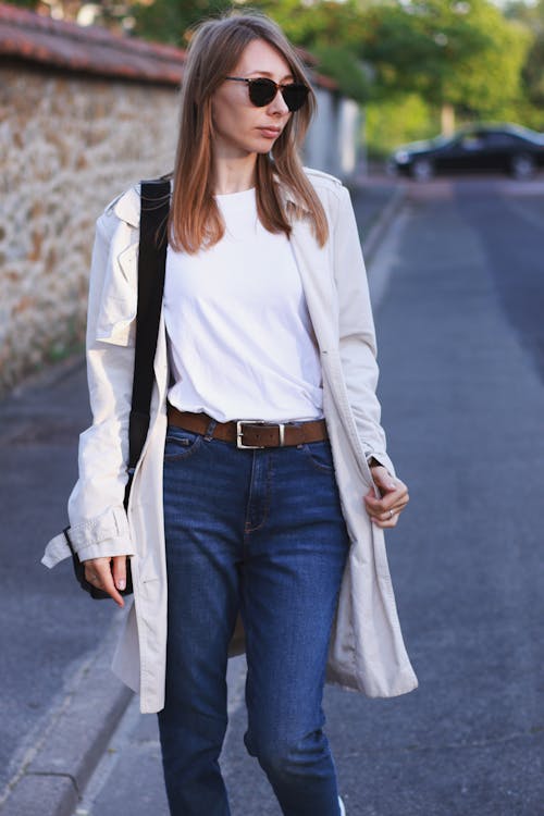 A woman in jeans and a white shirt is walking down the street