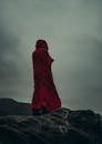 A person in a red cloak standing on a rock