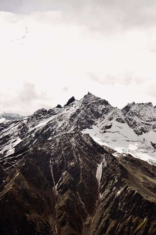 Free Snowcapped peaks in a dramatic mountain range under a cloudy sky. Stock Photo