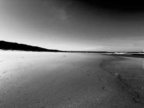 A tranquil black and white beach scene with expansive sand and gentle ocean waves