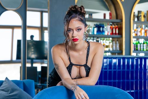 Free Stylish woman in black dress with red lips posing at a modern bar, exuding confidence and allure. Stock Photo