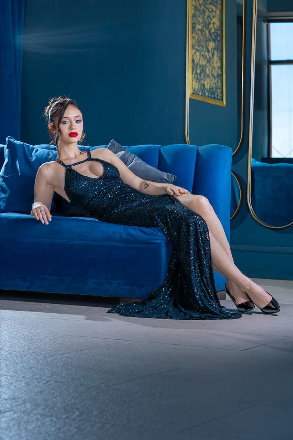Woman in a black sequin dress posing on a sofa