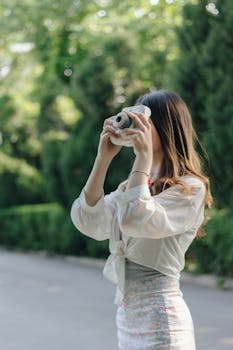 一名女子在绿意盎然的户外用拍立得拍照
