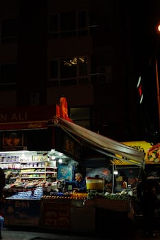 A bustling night market stand under streetlights selling various snacks and beverages.