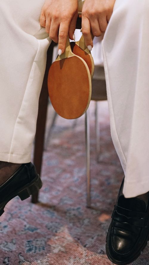 Free Close-up of a woman holding table tennis rackets while sitting indoors, focusing on hands and equipment. Stock Photo