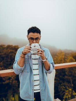 雾蒙蒙的天气里，一位时尚的年轻人在户外喝着咖啡，放松身心