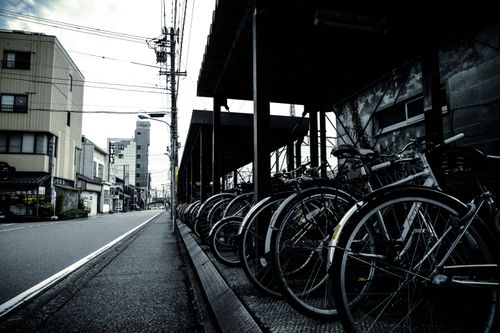Free A row of parked bicycles along an urban street, showcasing city life and transportation. Stock Photo