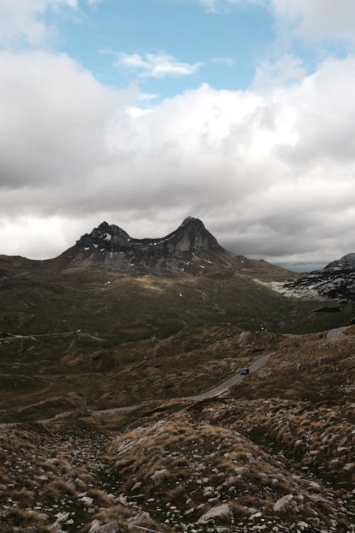 A mountain range with a cloudy sky and a road