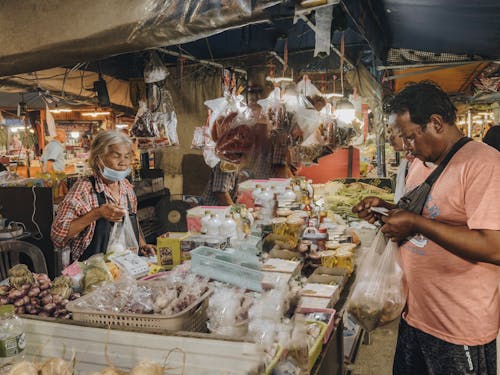 Two people are shopping in a market with food