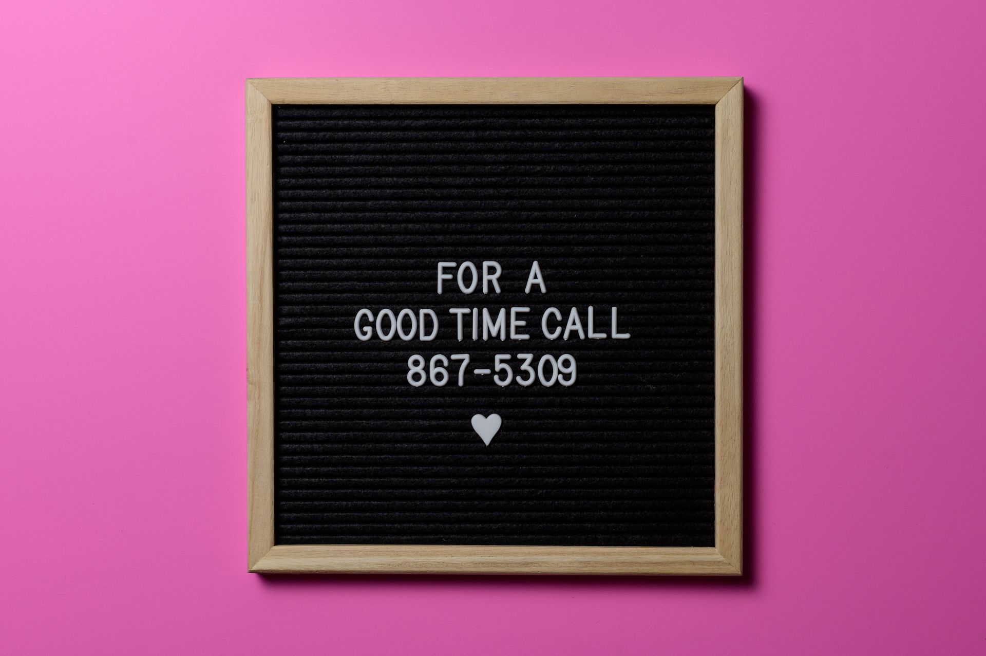 Wooden letter board with playful message against a pink background.