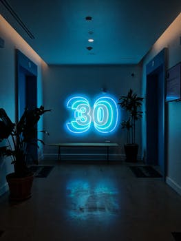 明亮的现代走廊里，霓虹灯“30”标志与植物相映成趣，营造出时尚的氛围