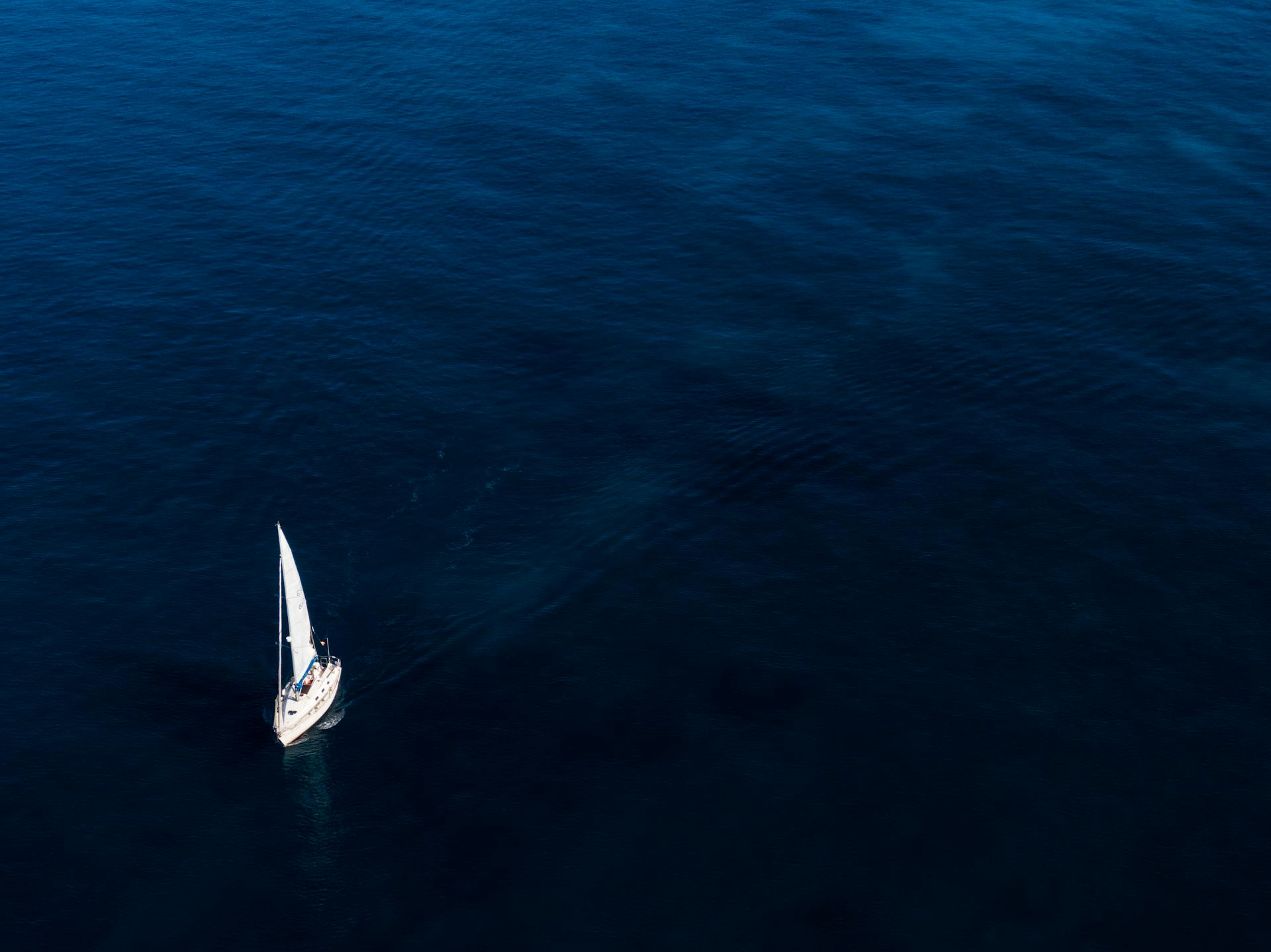 White Boat Sailing On Body Of Water