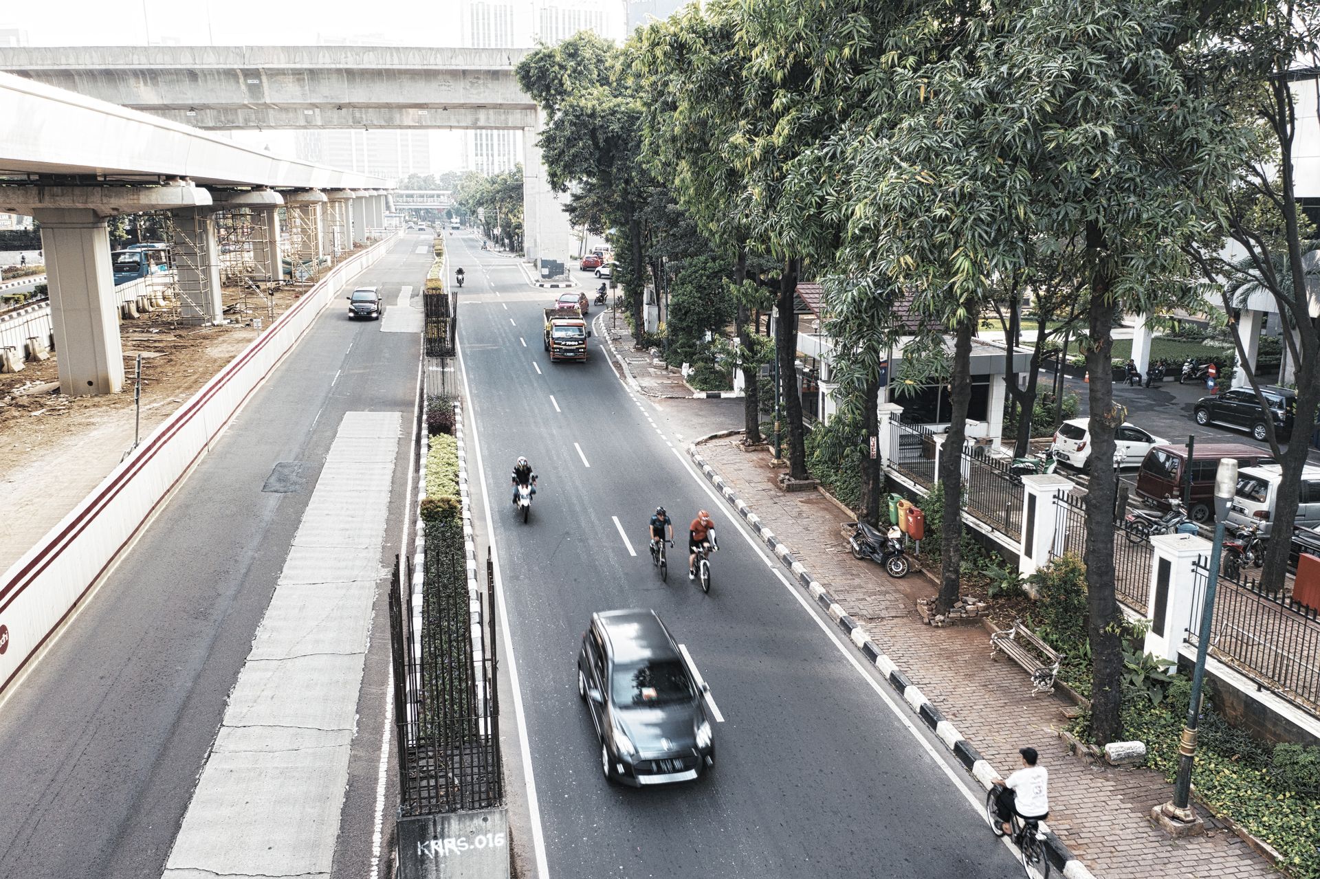 Aerial shot of vehicles on a city road with trees and infrastructure.