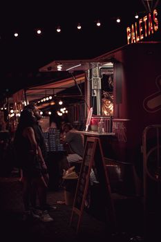 People enjoying a night out at a food truck, creating a vibrant urban atmosphere.