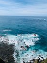 从空中俯瞰，海岸线岩石崎岖，海浪碧绿，天空湛蓝清澈
