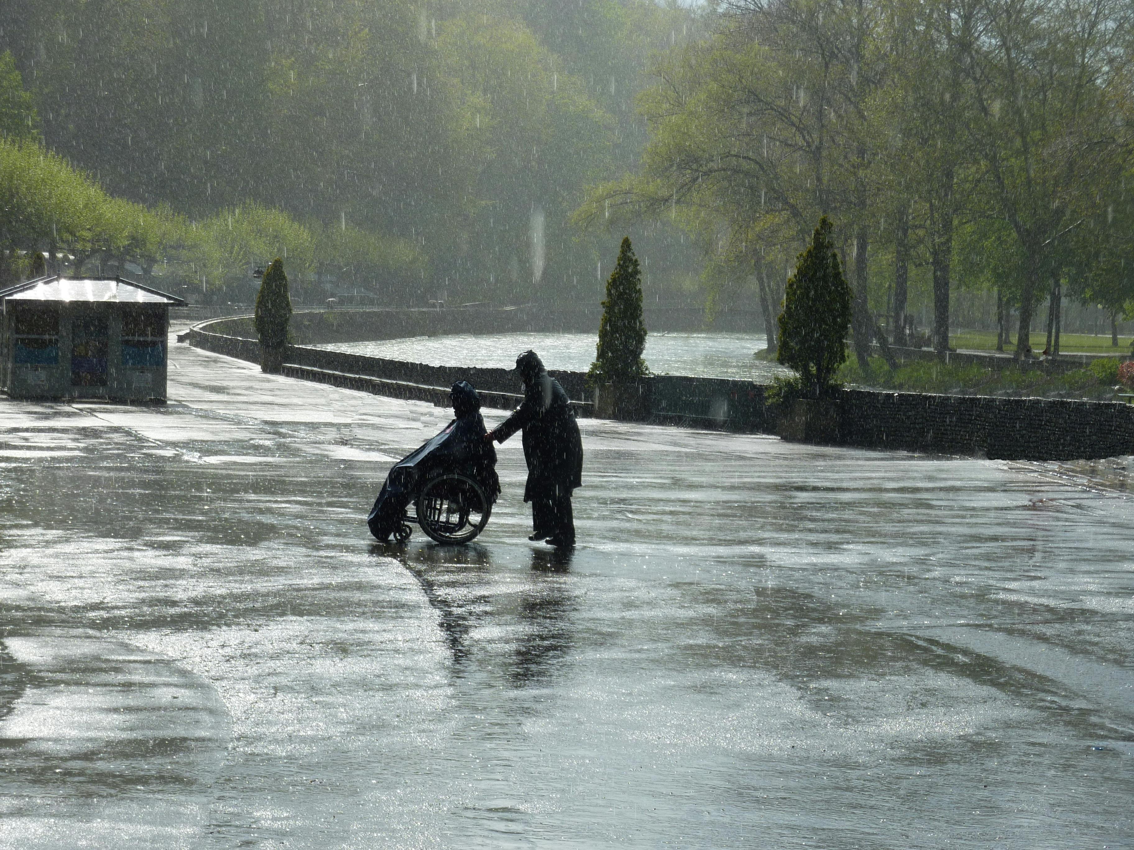 Caretaker Pulling Person on Wheelchair in Rain · Free Stock Photo