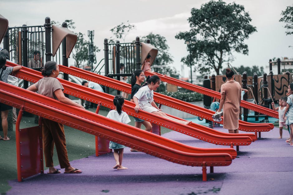 Children playing safely on a colorful rubber bark playground in a community park - rubber bark play area Charlotte NC Children playing safely on a colorful rubber bark playground in a community park - rubber bark play area Charlotte NC