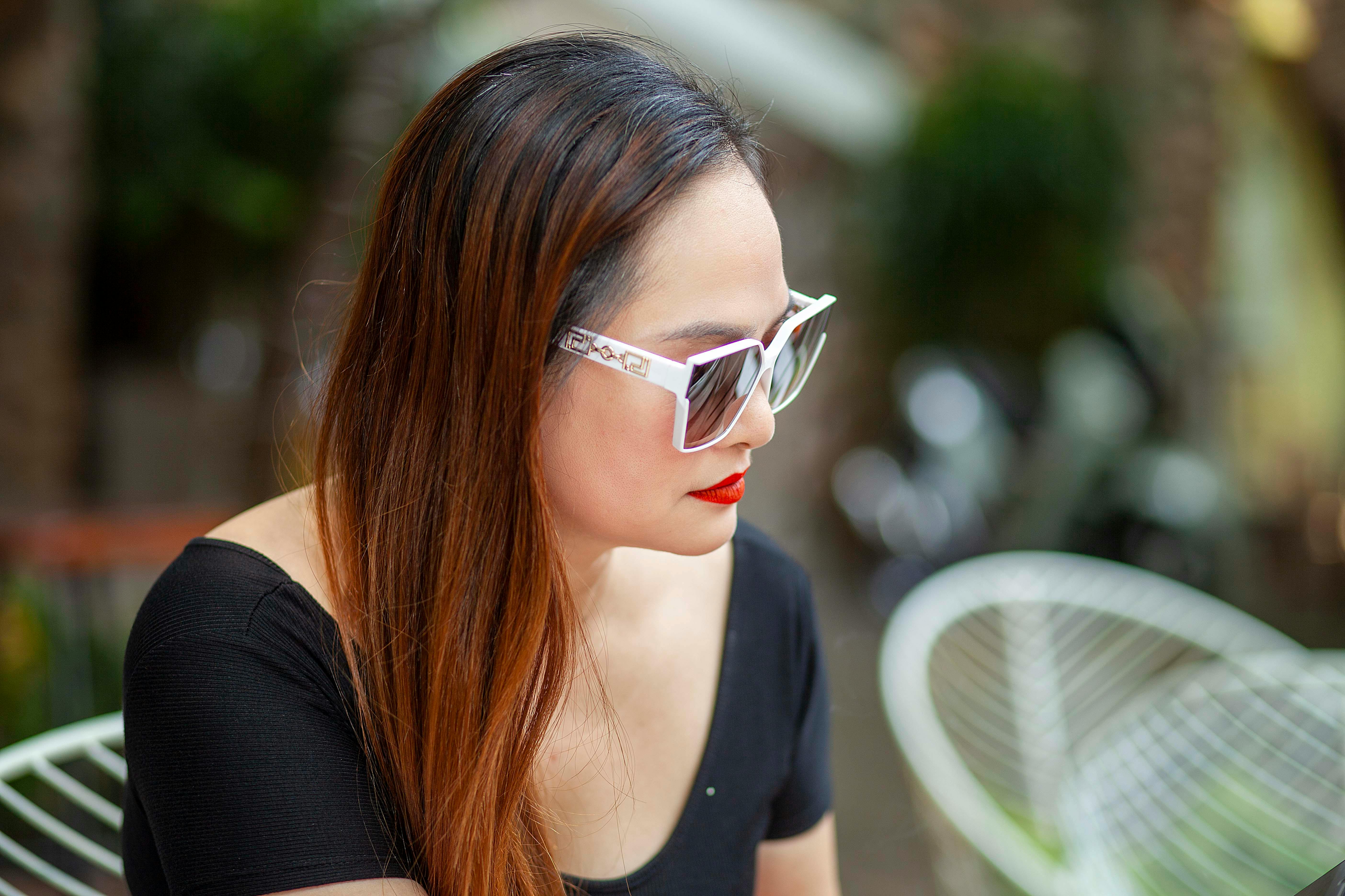 Free A serene moment as a woman in sunglasses relaxes outdoors, exuding elegance and style. Stock Photo