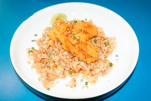 A plate of fried fish with rice and lime