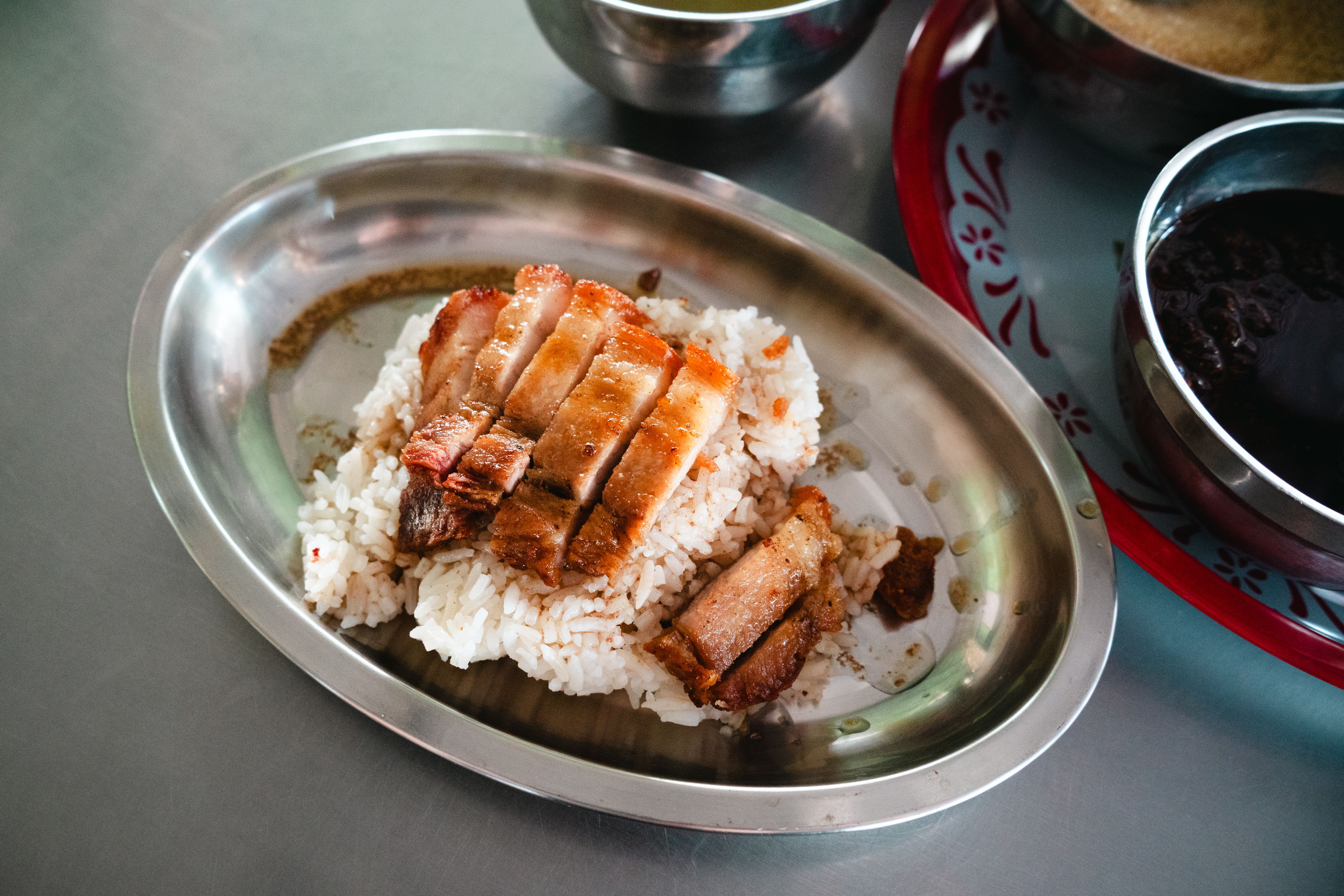 A close-up of crispy pork served with fluffy rice on a metal tray, perfect for food photography.