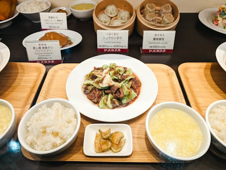 Various Asian dishes including dumplings and rice on a buffet with detailed labels.