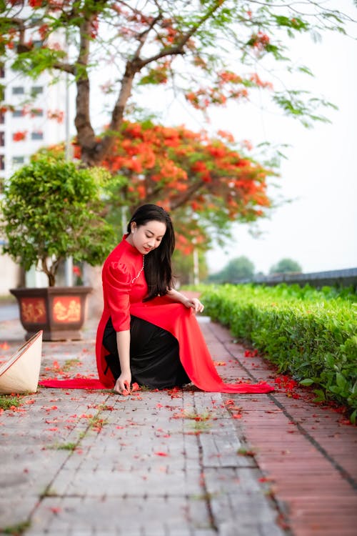 A woman in a red dress sitting on the ground