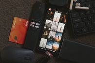 Flat lay of a smartphone, remote control, credit card, and gadgets for a tech-savvy lifestyle.