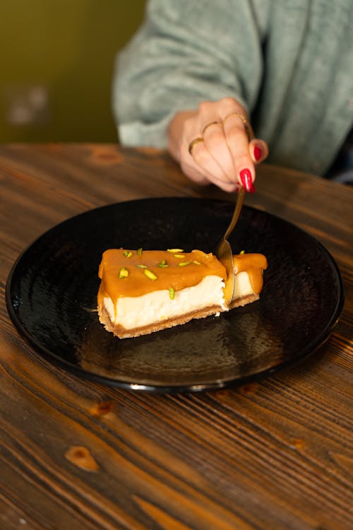 A person eating a slice of cheesecake on a plate
