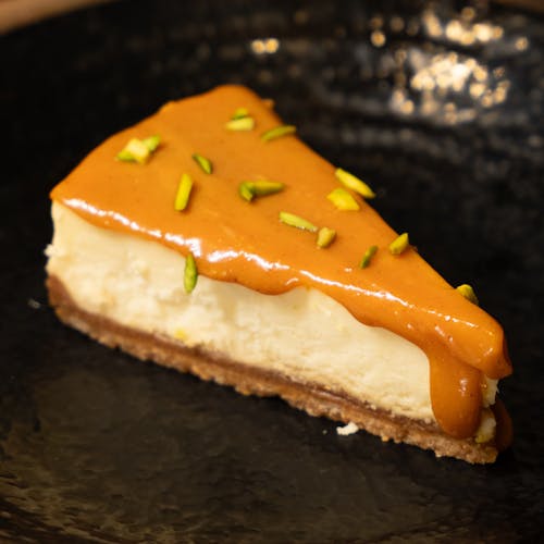 A slice of cheesecake with caramel sauce and pistachio