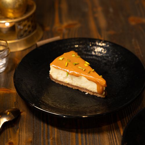 Free A rich cheesecake slice topped with caramel and sprinkled with pistachios on a modern black plate. Stock Photo