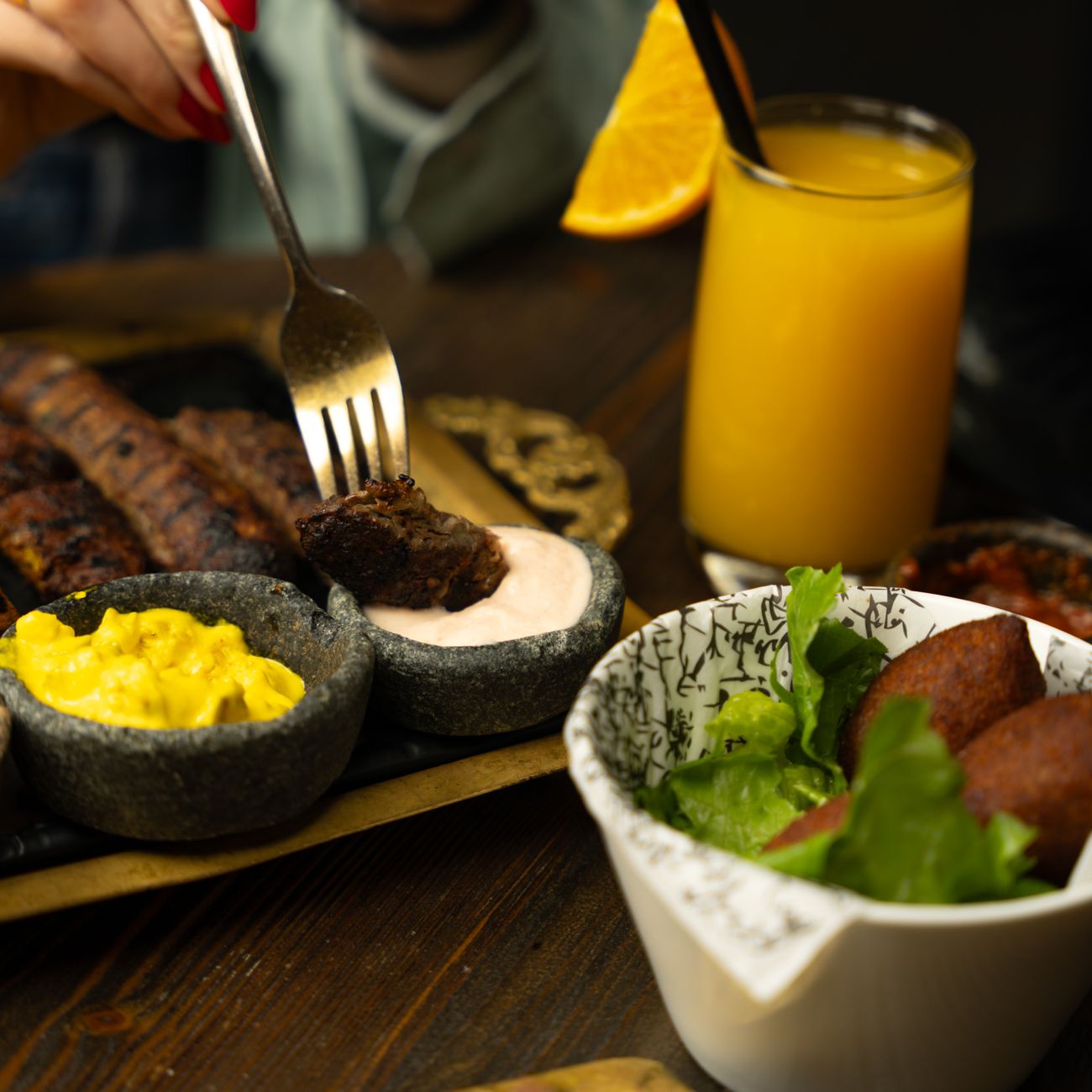 Grilled meat with dipping sauces and fresh juice at a restaurant