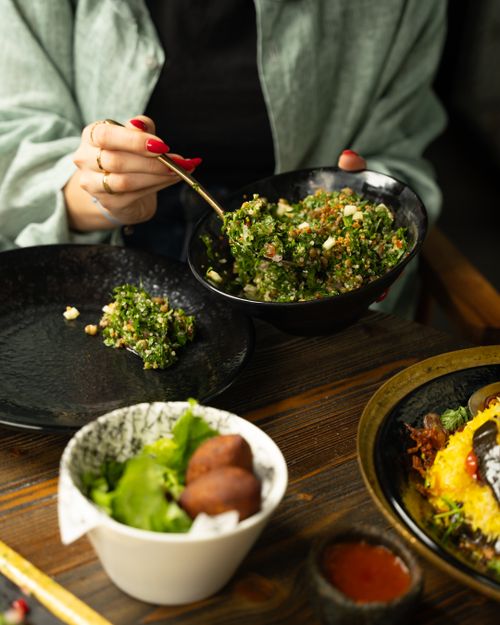 Free Close-up of a woman enjoying a fresh tabbouleh salad in a cozy restaurant setting. Stock Photo