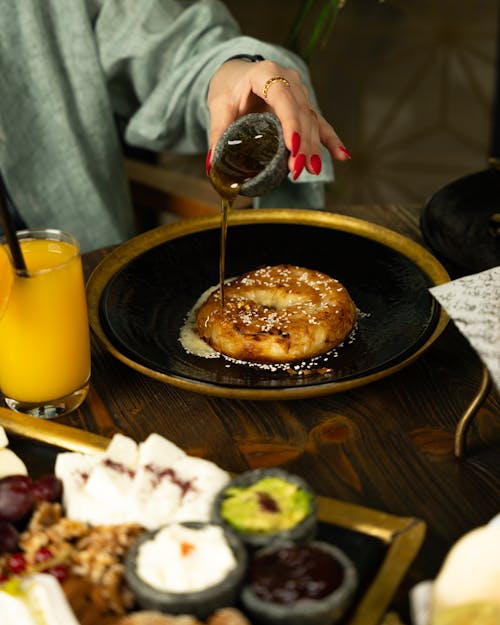 A woman is pouring syrup on a breakfast plate