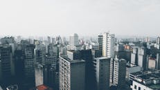 一张多云天空下密集都市风景的鸟瞰图，图中可见众多摩天大楼和高层建筑