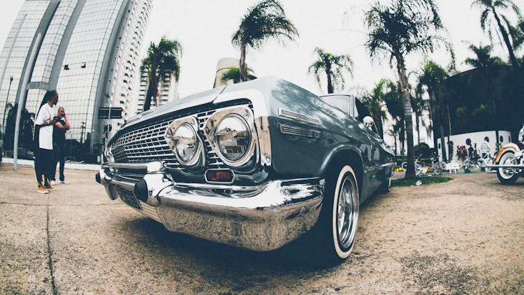 Classic Blue Chevrolet Impala Parked Beside Man