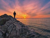 在日本令人惊叹的日出时分，一个人影站在海边的岩石上