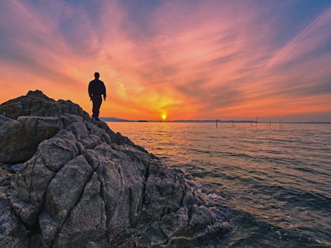 在日本令人惊叹的日出时分，一个人影站在海边的岩石上