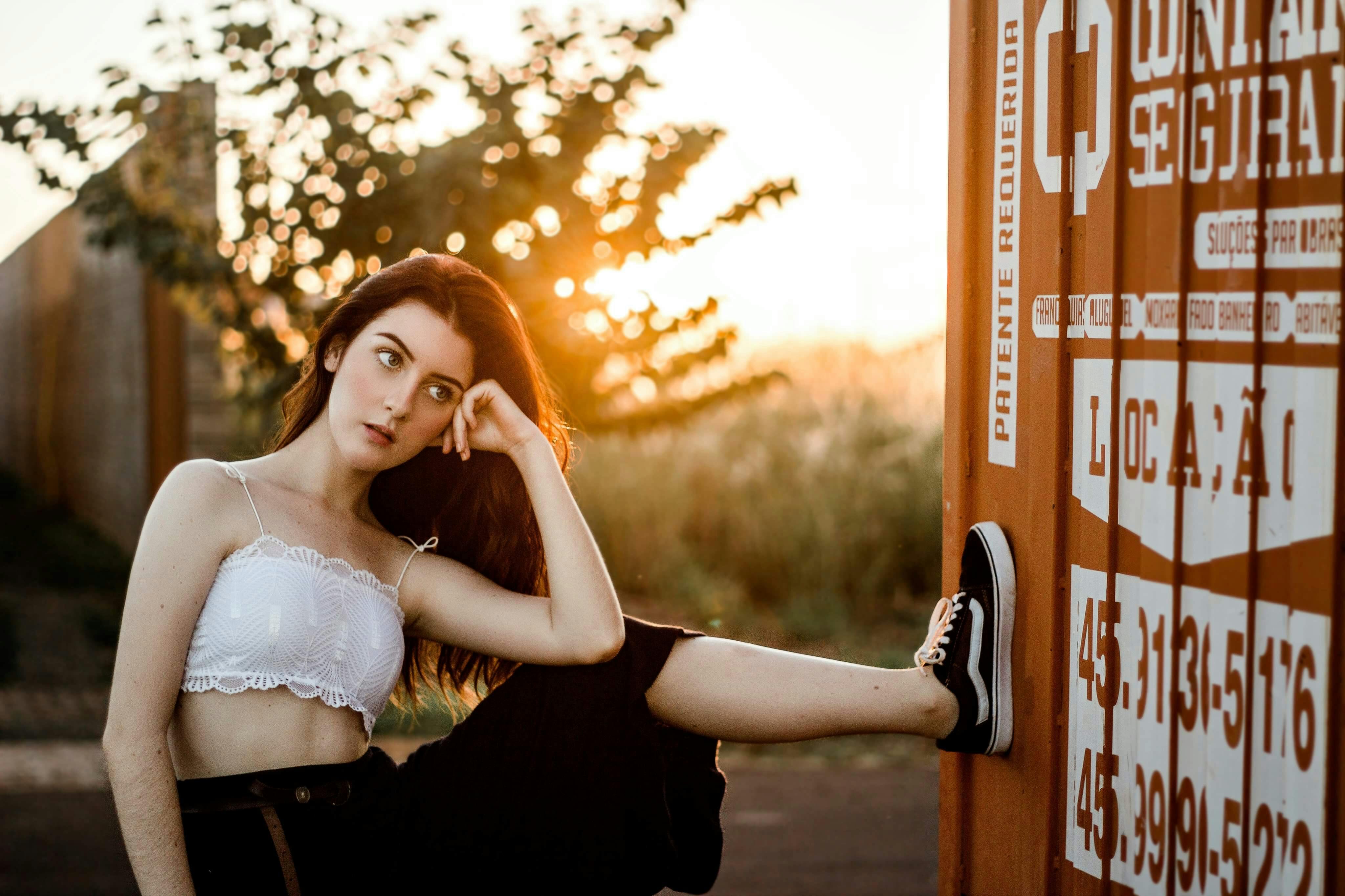 日落时分，一位年轻女子在容器旁若有所思地摆着姿势，神情随意而沉静