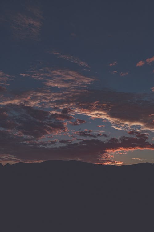 бесплатная Малиновые облака в голубом небе во время заката Стоковое фото