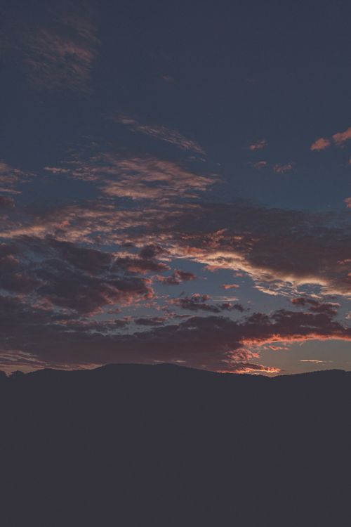 Free Vibrant sunset with colorful clouds over mountain landscape, showcasing nature's beauty. Stock Photo